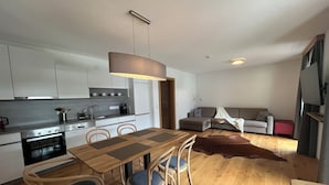 Une cuisine moderne avec un coin repas, un plancher en bois et un espace de vie chaleureux comprenant un canapé et un tapis.