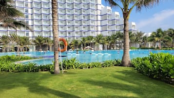 Relax by the hotel's large rectangular pool surrounded by lush greenery and palm trees.
