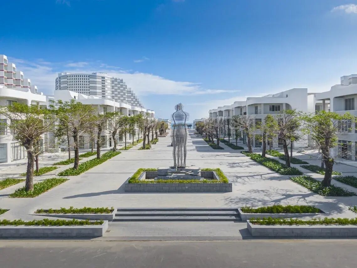 Un hôtel moderne doté d’une sculpture centrale, de larges allées et d’un aménagement paysager symétrique.