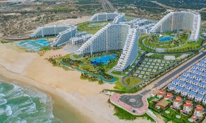 A resort with multiple high-rise buildings, a central pool area, and a beach.