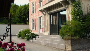 Une maison à deux étages avec une façade rouge et blanche, un porche à l’avant et une allée gravillonnée.