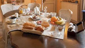 Une table de petit-déjeuner dressée avec des croissants, des fruits et du café.