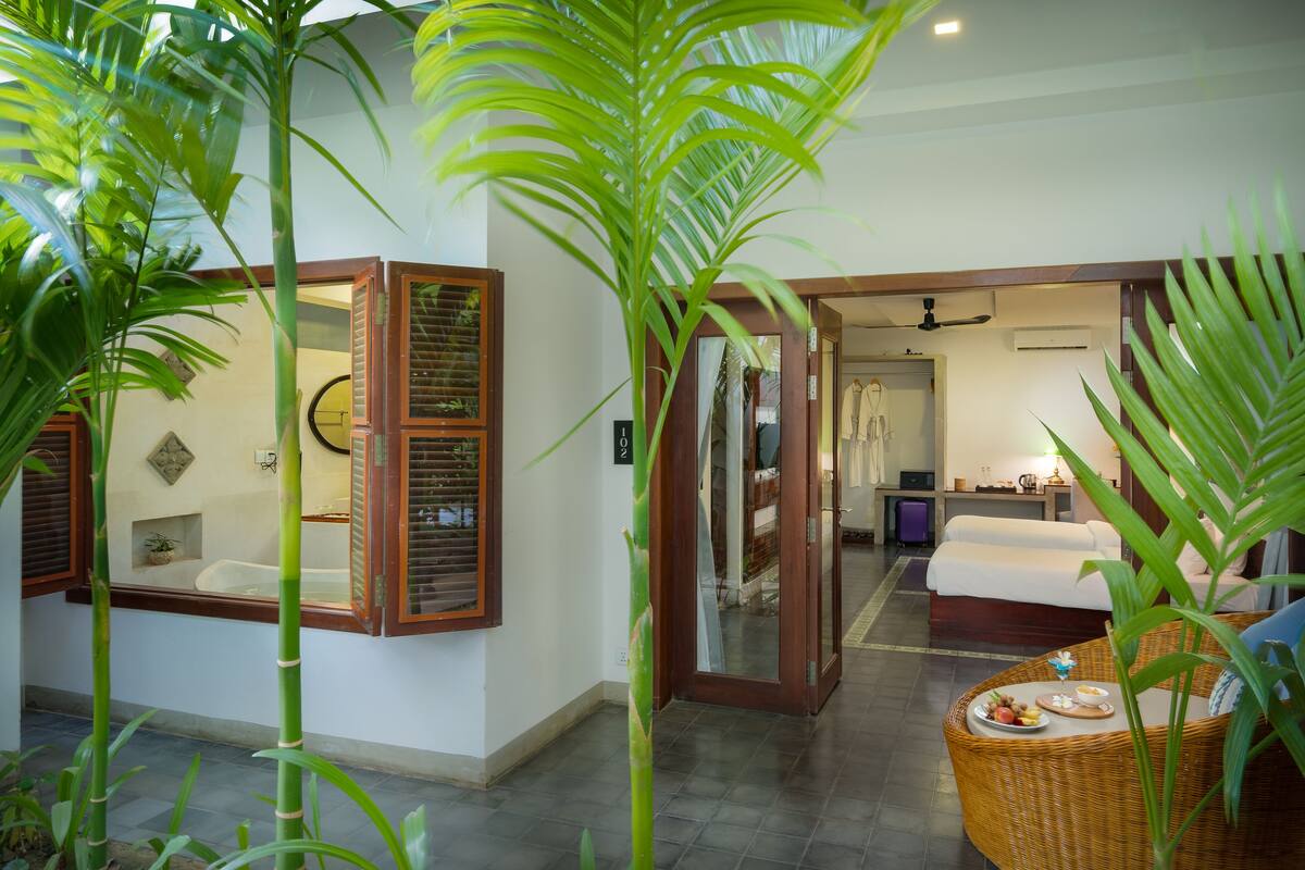 Quarto de hotel com cama, cadeira de vime e mesa de jantar com comida.