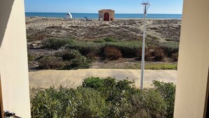 Vista de una playa con un pequeño edificio, un farol y algo de vegetación.