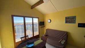 Un comedor con una mesa, sillas, un sofá y vistas amplias por un ventanal.