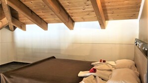 A single bed with a brown cover, white pillows, and a red flower. - Ιndependent stone apartment with attic. (Παλαιλώνι βαμου)