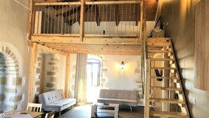 A rustic wooden interior with a loft bedroom, a sofa, a dining table, and a staircase. - Ιndependent stone apartment with attic. (Παλαιλώνι βαμου)