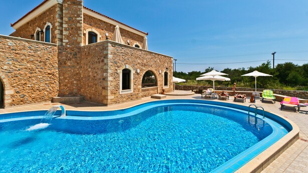 A swimming pool with a stone building in the background. - Ιndependent stone apartment with attic. (Παλαιλώνι βαμου)