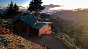 A wooden cabin with a metal roof, surrounded by a mountainous landscape and a clear sky. - Full house with breathtaking views (San José)