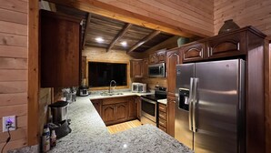 A modern kitchen with granite countertops, stainless steel appliances, wooden cabinets, and a large window. - Full house with breathtaking views (San José)