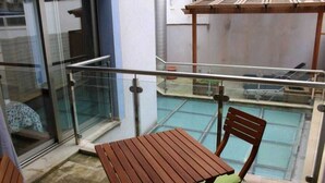 A balcony with a glass railing, a wooden table, and a chair.