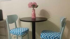 A small round table with a black base and two chairs with blue and white patterned cushions. A pink vase with flowers is placed on the table. - Cottage at West 7 Palms  (St. Thomas)