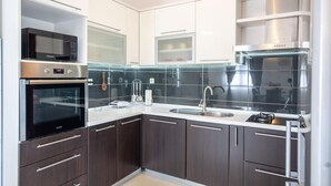 Et moderne køkken med mørke træskabe, rustfrie stål hvidevarer og en sort backsplash.