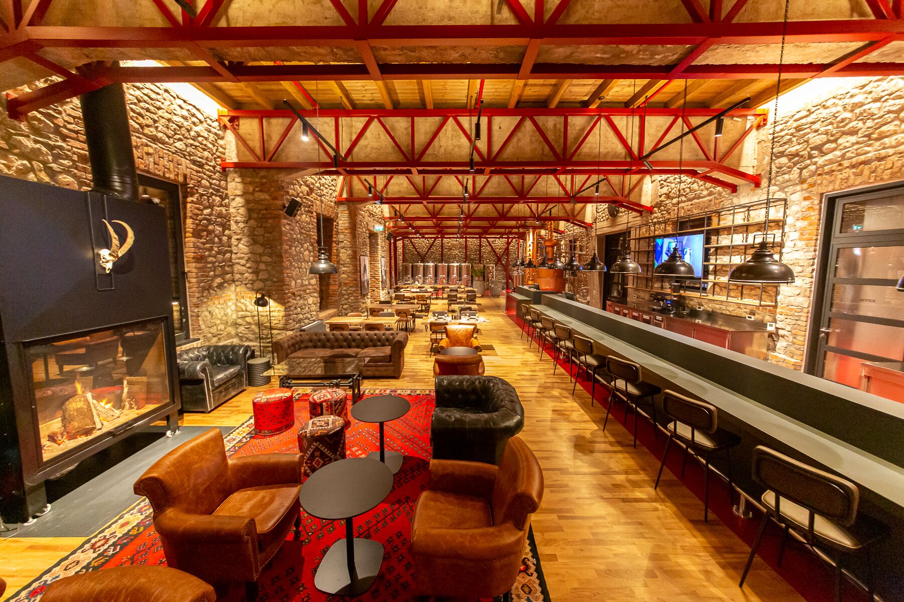 A spacious lounge area with a fireplace, leather sofas, and a long bar counter.