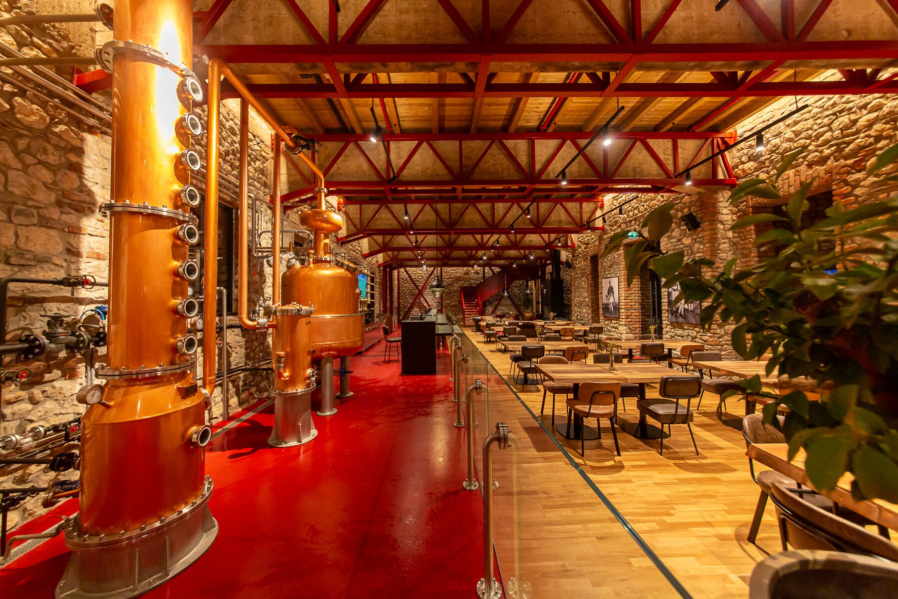 A spacious restaurant with a long counter, multiple tables, and a stone wall backdrop.