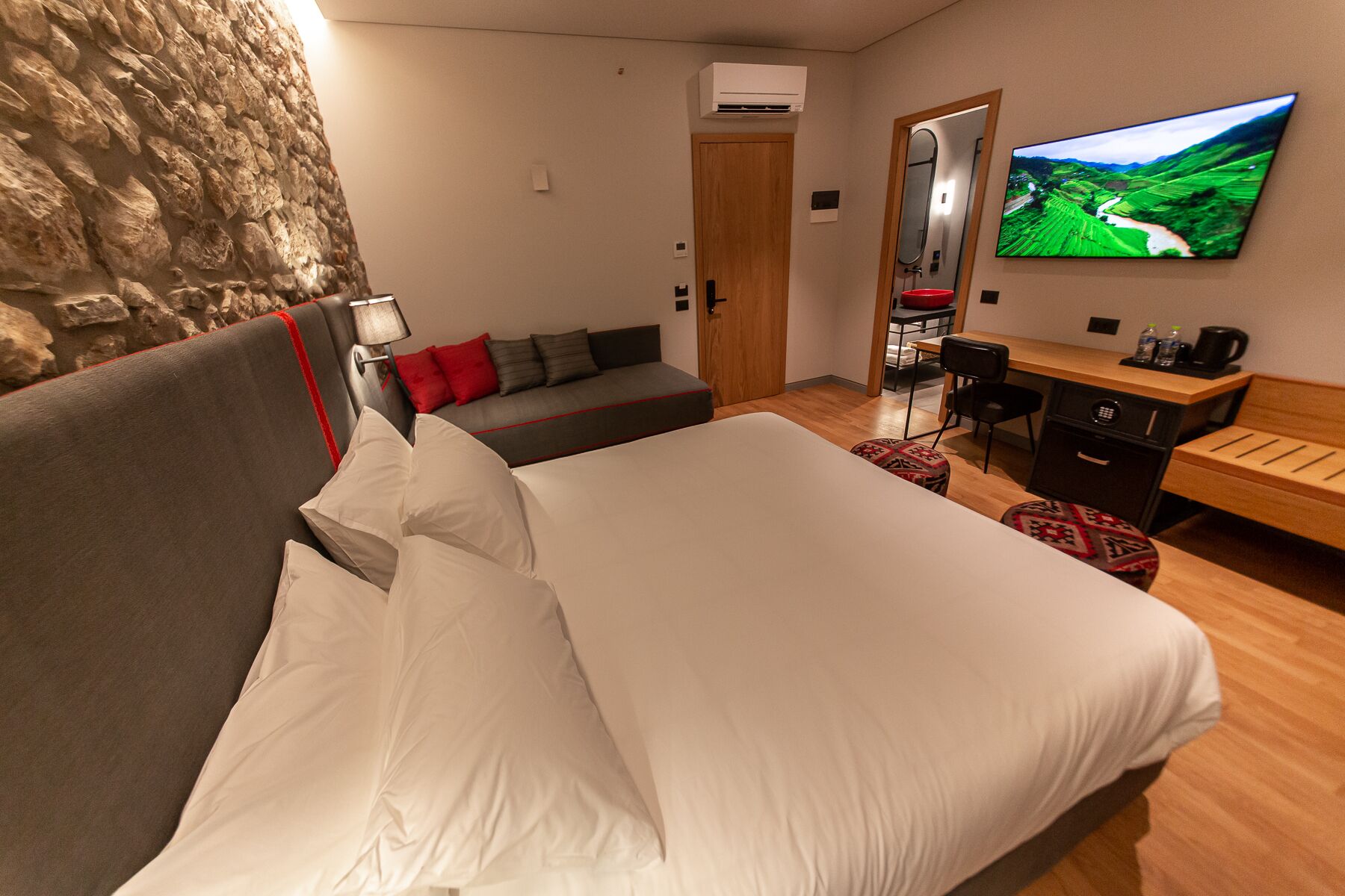 Ett hotellrum med en stor säng, en soffa, ett skrivbord, en stol och en tv på väggen.