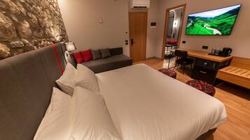 Ett hotellrum med en stor säng, en soffa, ett skrivbord, en stol och en tv på väggen.