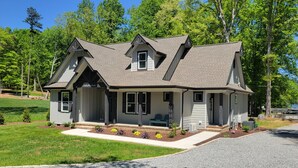 A two-story house with a gabled roof, a covered porch, and a well-maintained lawn. - Quiet lake getaway offering R&R with 2 electric bikes and optional sunset cruise (Sherrills Ford)