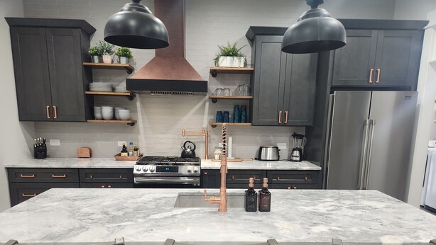 A modern kitchen with dark cabinetry, a central island with bar stools, stainless steel appliances, and pendant lighting. - Quiet lake getaway offering R&R with 2 electric bikes and optional sunset cruise (Sherrills Ford)
