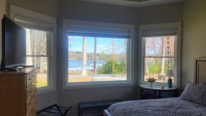 A bedroom with a large window, a bed, a TV on a dresser, and a lamp on a side table. - Quiet lake getaway offering R&R with 2 electric bikes and optional sunset cruise (Sherrills Ford)