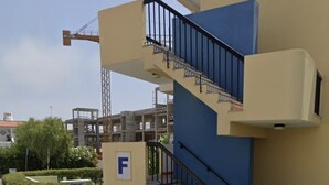 A building with a blue and beige facade, a staircase with black railings, and a sign with the letter 'F'. - Apartment center Albufeira (Albufeira)