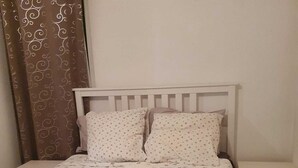 A bed with a white headboard, two pillows, a dark blanket, and two folded towels. - Apartment center Albufeira (Albufeira)