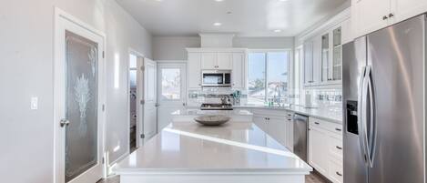 A modern kitchen with white cabinetry, stainless steel appliances, and a large island.