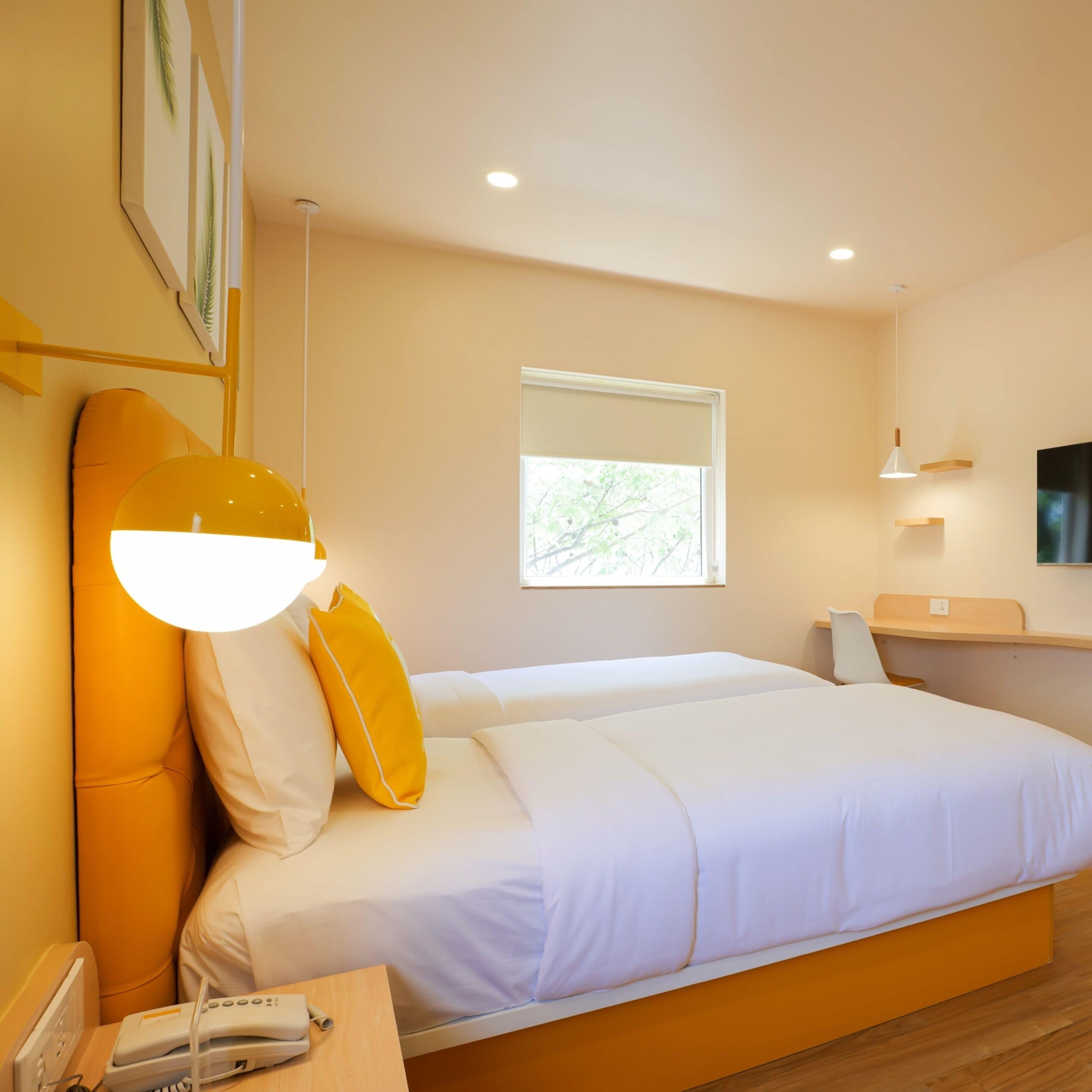 Una habitación de hotel moderna con una cama grande, una mesita de noche y un escritorio pequeño con una silla.