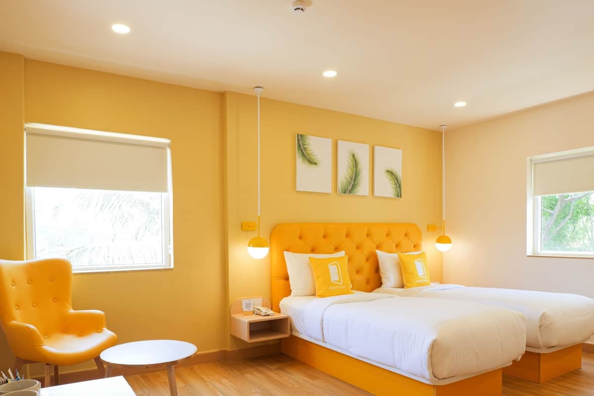 Ein Hotelzimmer mit einem großen Bett, einem Sessel, einem kleinen Tisch und Kunstwerken an der Wand.