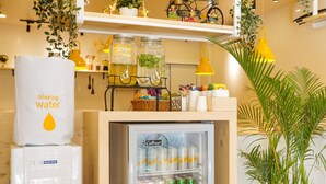 Ein kompakter Kühlschrank mit Getränken, ein Wasserspender und ein Topfpflanze.