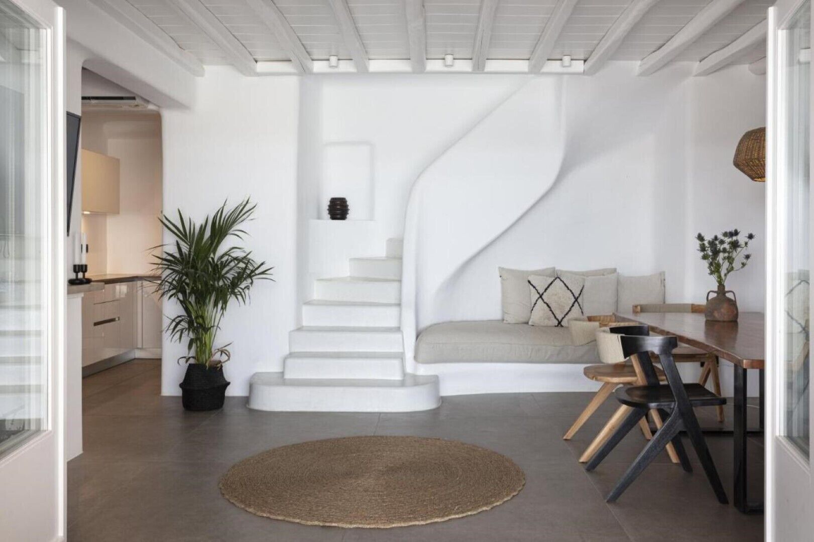 A modern interior with a spiral staircase, a dining area, and a kitchen.