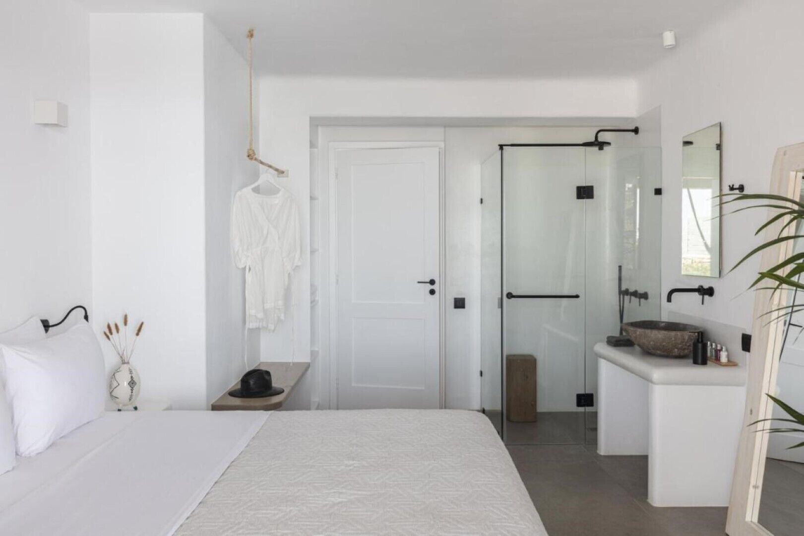 Una camera da letto moderna con un letto, un comodino e un bagno dotato di cabina doccia in vetro.