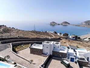 Un edificio costero con patio de piedra, paredes blancas y vistas al mar.