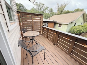 A wooden deck with a round table and metal chairs, surrounded by a wooden fence with string lights. - The Backyard Bungalow On The Trail -just minutes from downtown (Greenville)