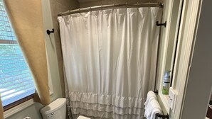 Ein Badezimmer mit Toilette, Duschvorhang und Handtuchhalter.