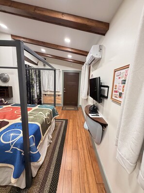 Une chambre d’hôtel avec un lit, un bureau, une télévision et une porte.