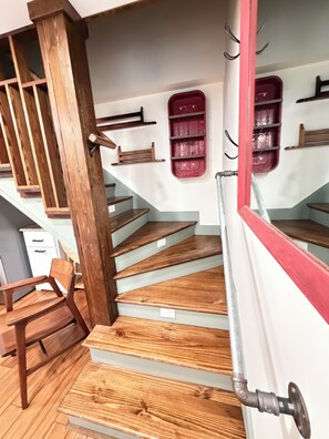 A wooden staircase with a metal handrail and a red accent wall.
