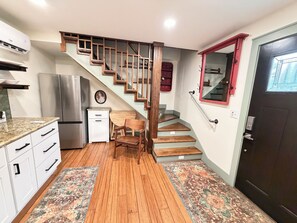 A kitchen with a built-in refrigerator, wooden staircase, and a door with a window.
