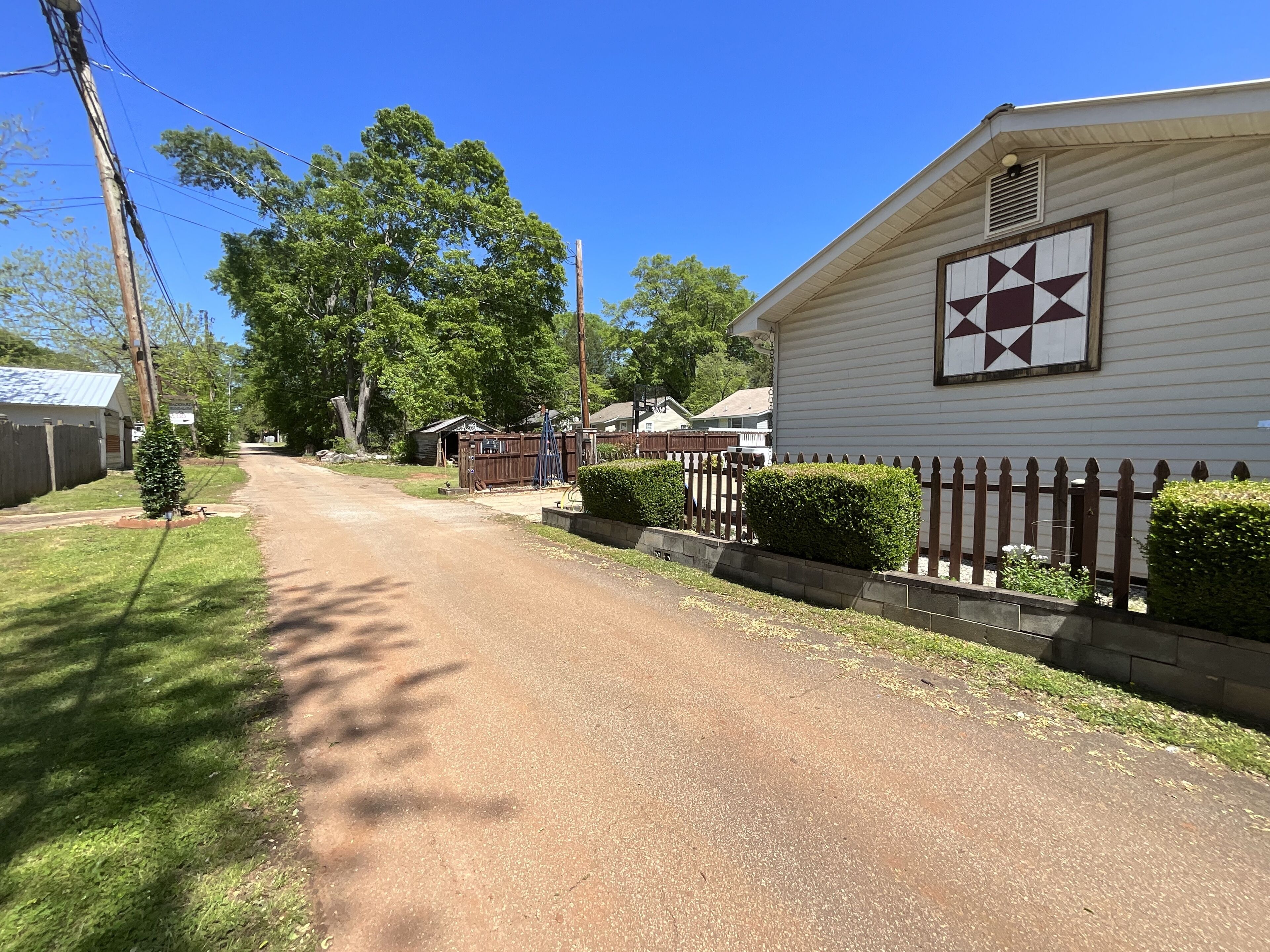 A residential street with houses, a wooden fence, and a clear blue sky.