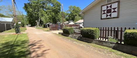 A residential street with houses, a wooden fence, and a clear blue sky.