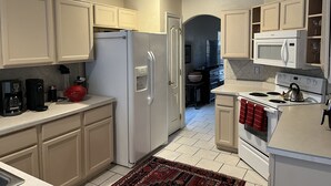 A kitchen with white cabinets, a refrigerator, a microwave, a stove, and a coffee maker. - Spacious, Comfortable Home Near Golf, Biking, Hiking & Restaurants (Tucson)