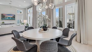 Ein moderner Essbereich mit einem runden Tisch, sechs Stühlen und einer Orchidee in der Mitte.