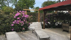 A wooden deck with two lounge chairs and a pergola structure. - Classified 4★ Landes house with swimming pool, in town center and beach nearby. (Messanges)