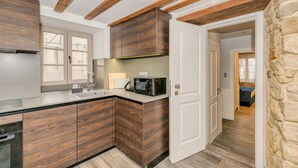A modern kitchen with wooden cabinetry, a built-in microwave, and a stone wall. - Mint Luxury Rooms (Split)