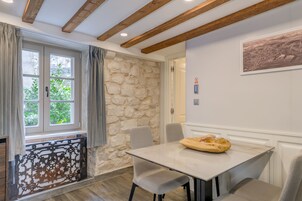 Un comedor con pared de piedra, una mesa con sillas y una ventana con cortinas.