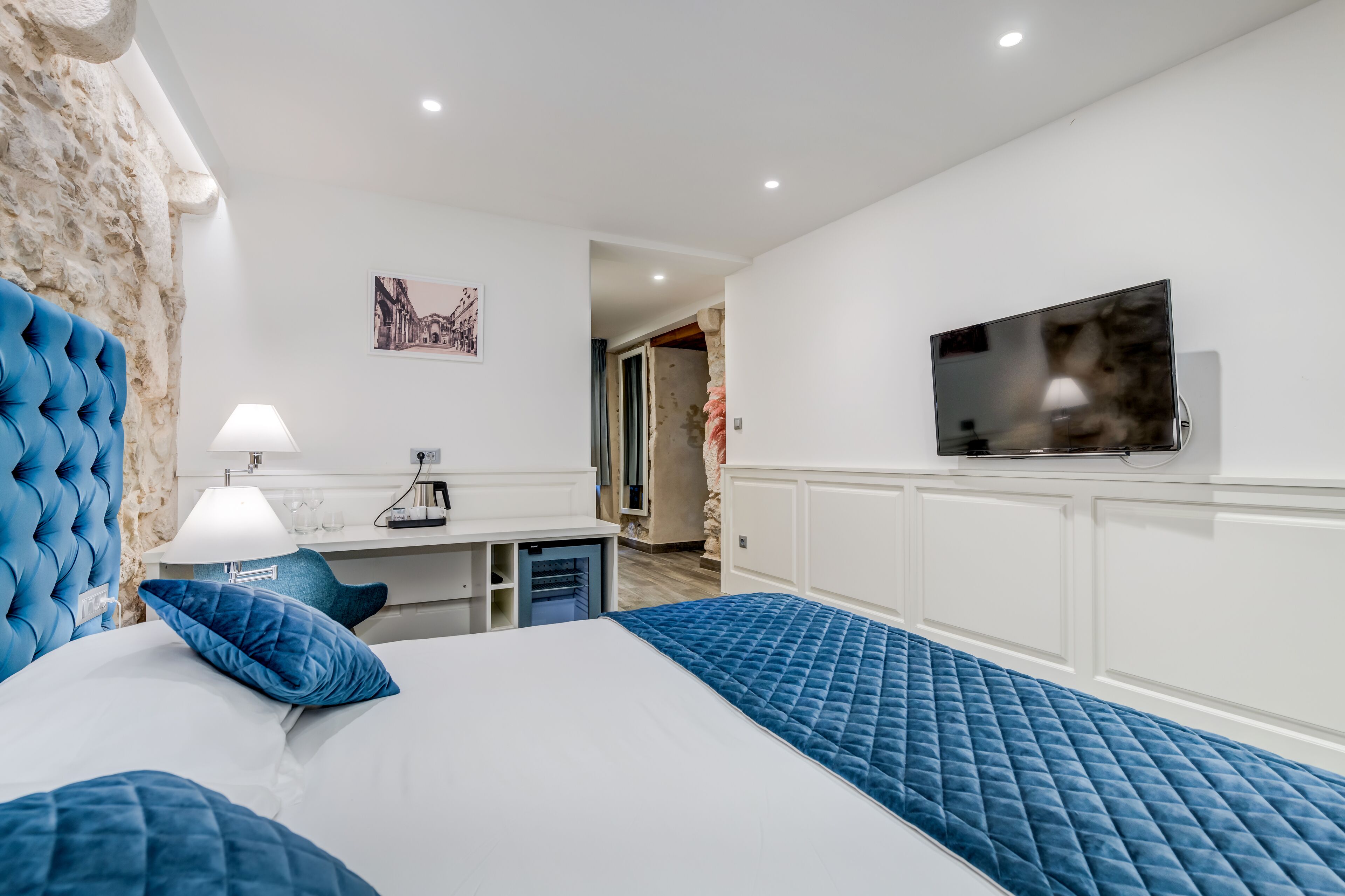 A modern bedroom with a large bed, a desk, and a TV.