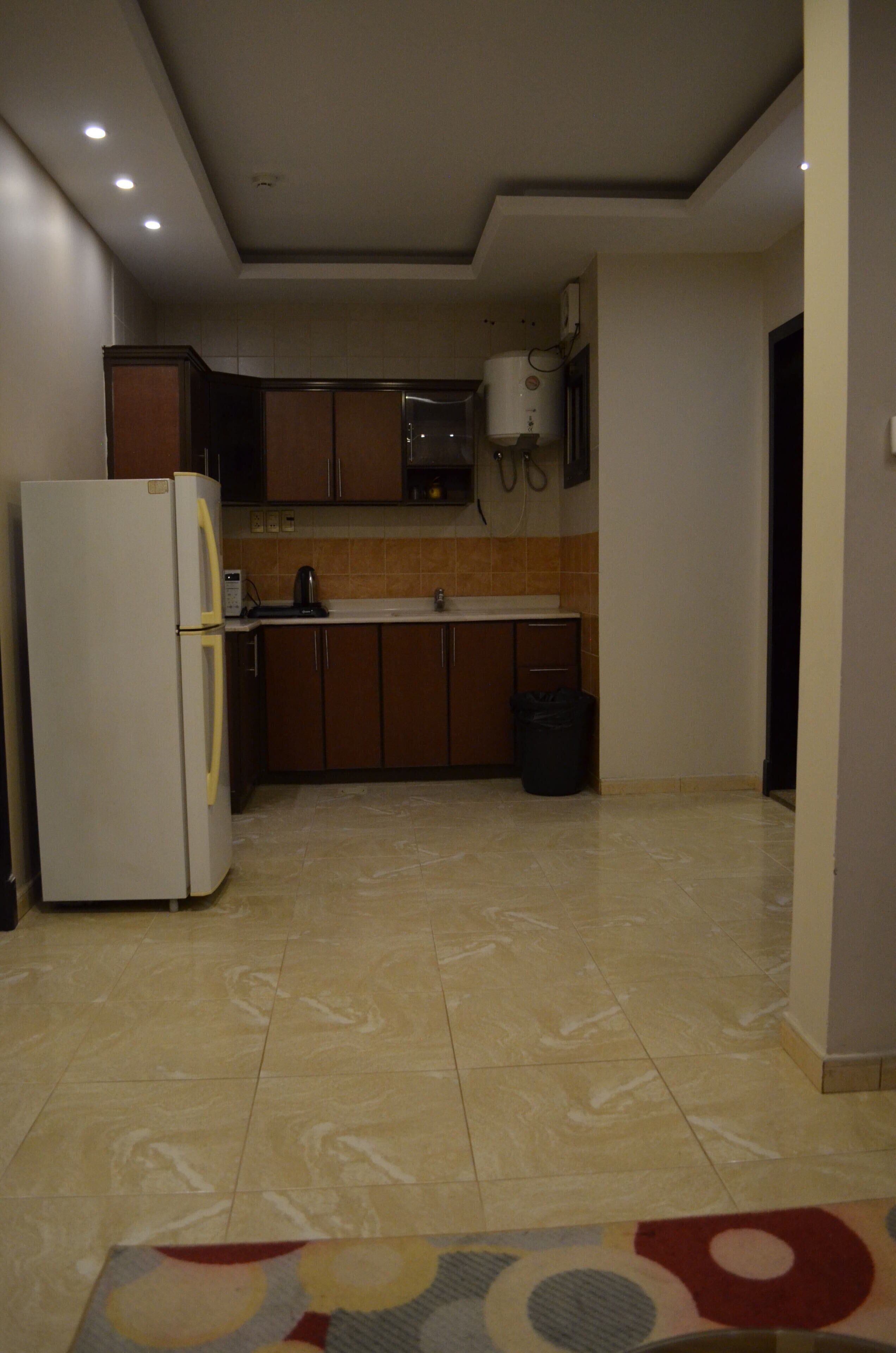 A kitchen with a refrigerator, cabinets, a sink, and a water heater.
