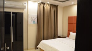 Una habitación de hotel con cama, armario, un cuadro y una cortina.