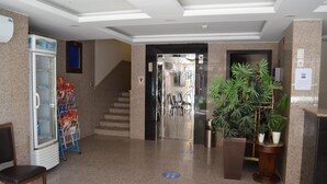 Un hall de hotel con un refrigerador lleno de bebidas, una escalera y plantas en macetas.
