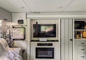 A compact living space with a television, a fireplace, and a kitchenette area. - Lakeside Hideaway with Romantic Vibes! Boat dock-boardwalk. Private boat launch. (Newport)